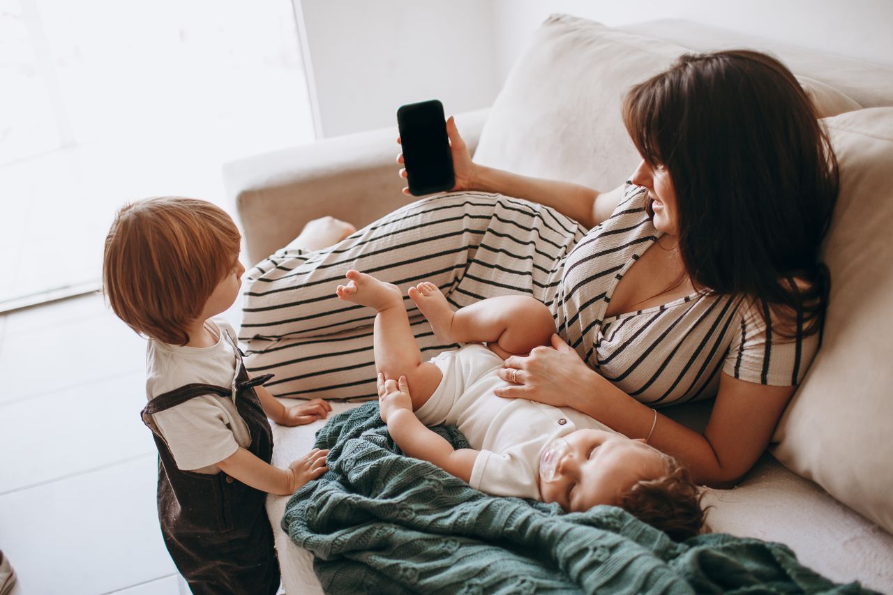 A mother enjoying time with her children on a comfortable couch, creating a warm, family atmosphere.